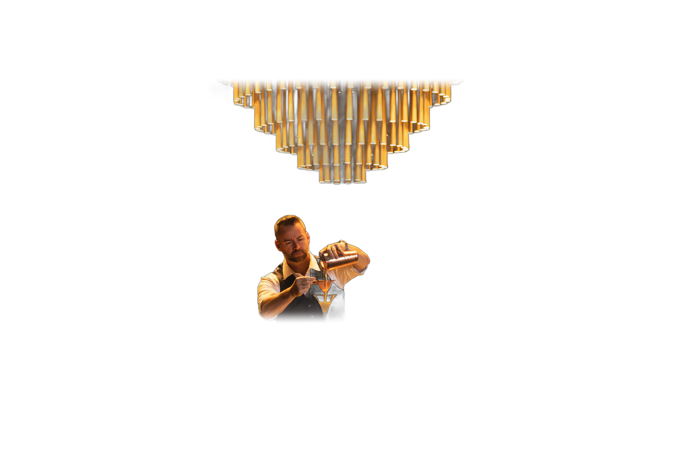 Bartender mid-pour beneath the chandelier — photographed by Daniel Kamen