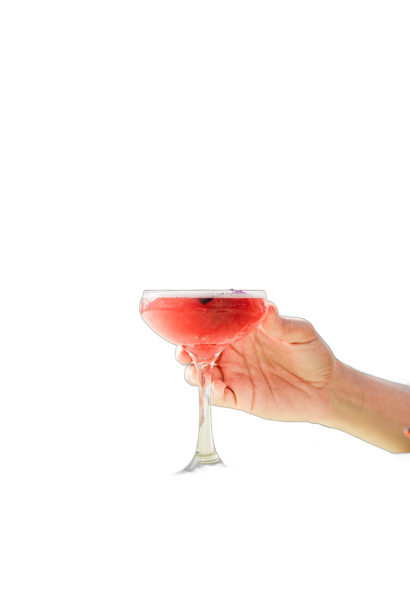 A hand raising a coral coupe cocktail on a rooftop terrace