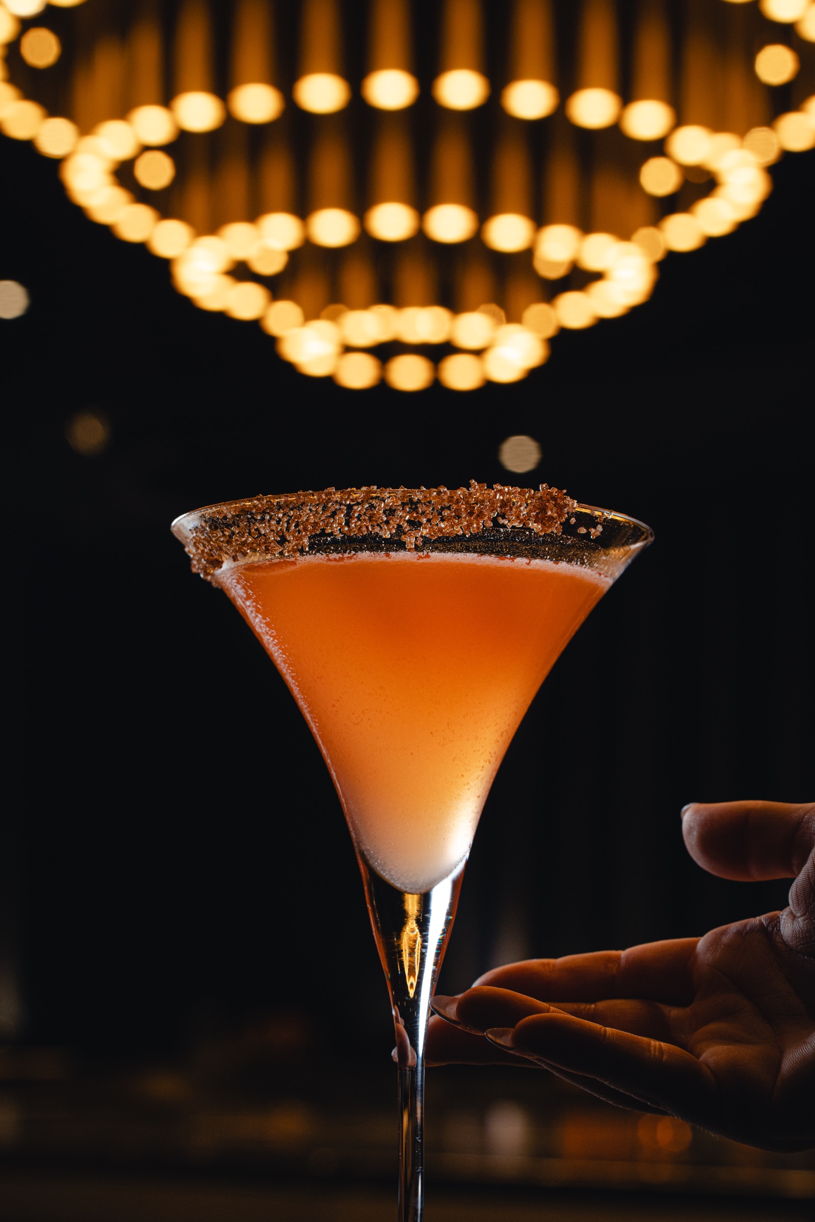 Orange cocktail beneath warm circular lights