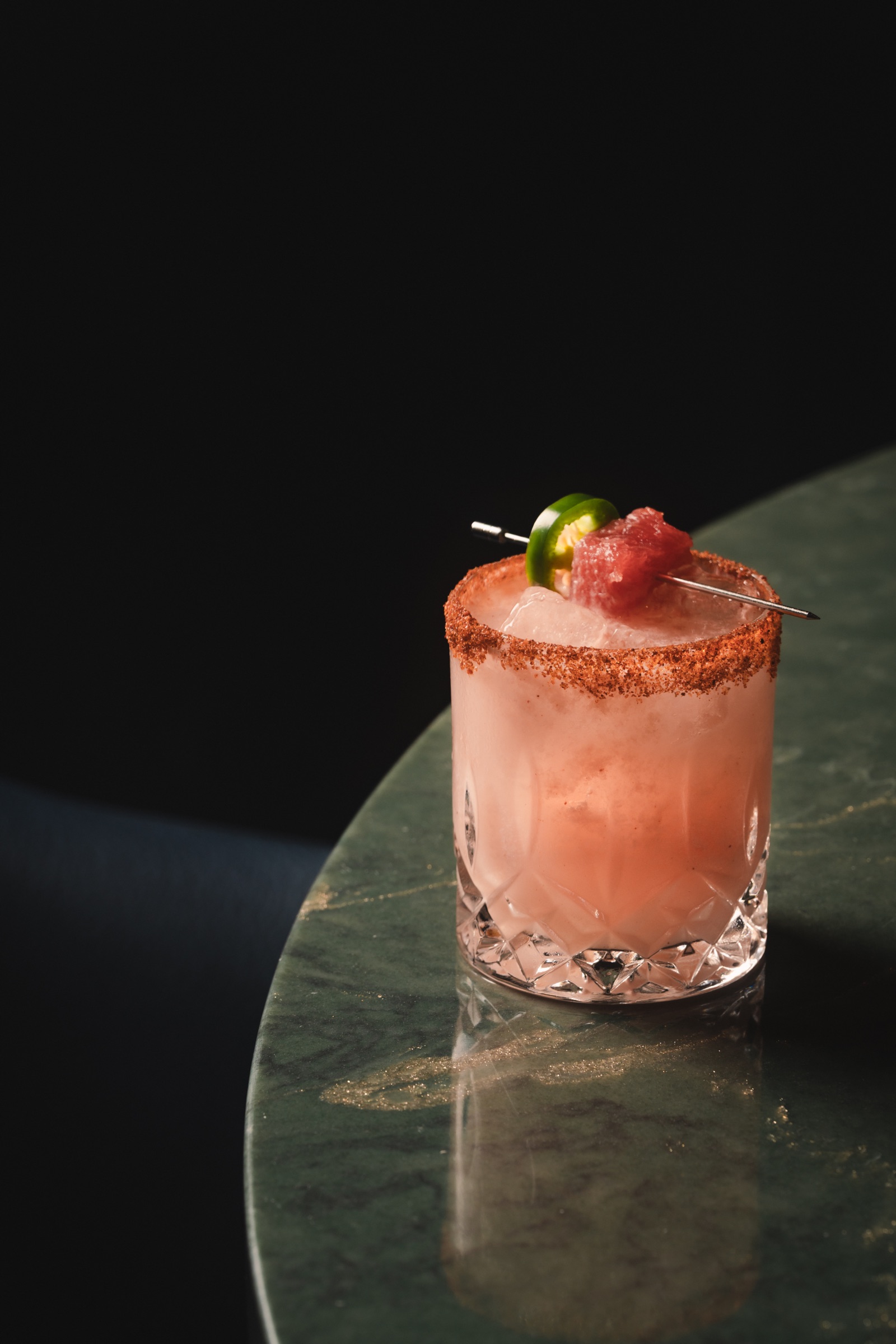Pink cocktail with a spiced rim on a green stone table